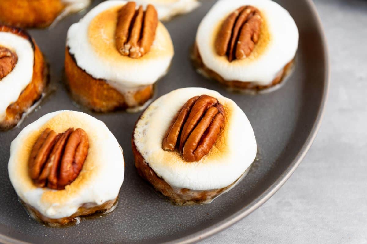 Close-up photo of a sweet potato bites on a plate with toasted marshmallows and pecans on top.