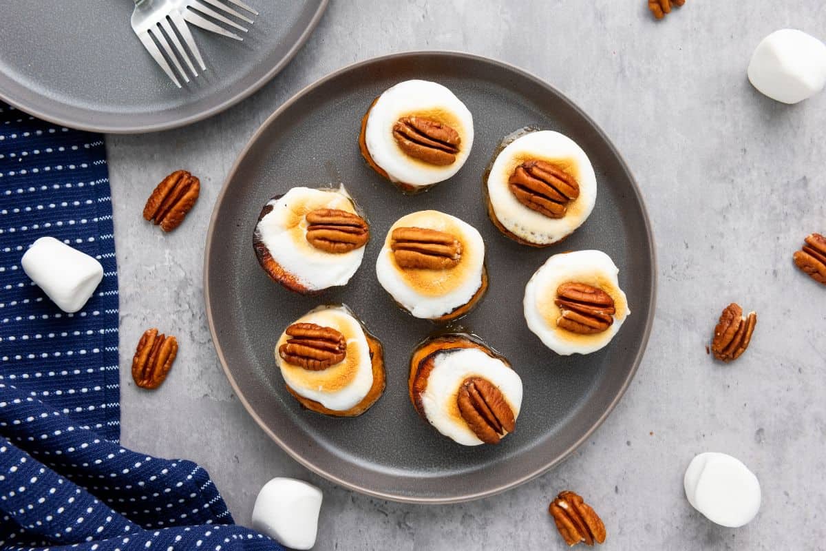 Sweet potato bites on a plate with toasted marshmallows and pecans on top.