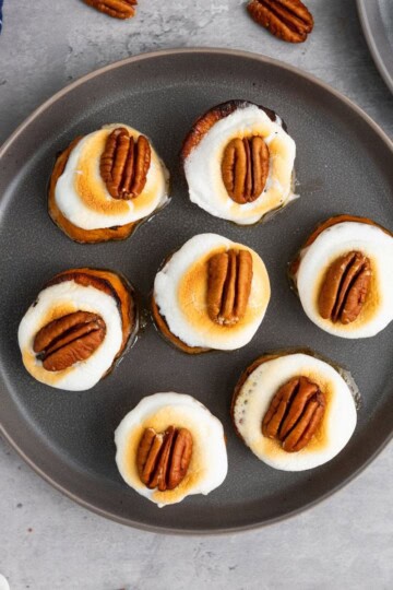 Sweet potato bites on a plate with toasted marshmallows and pecans on top.
