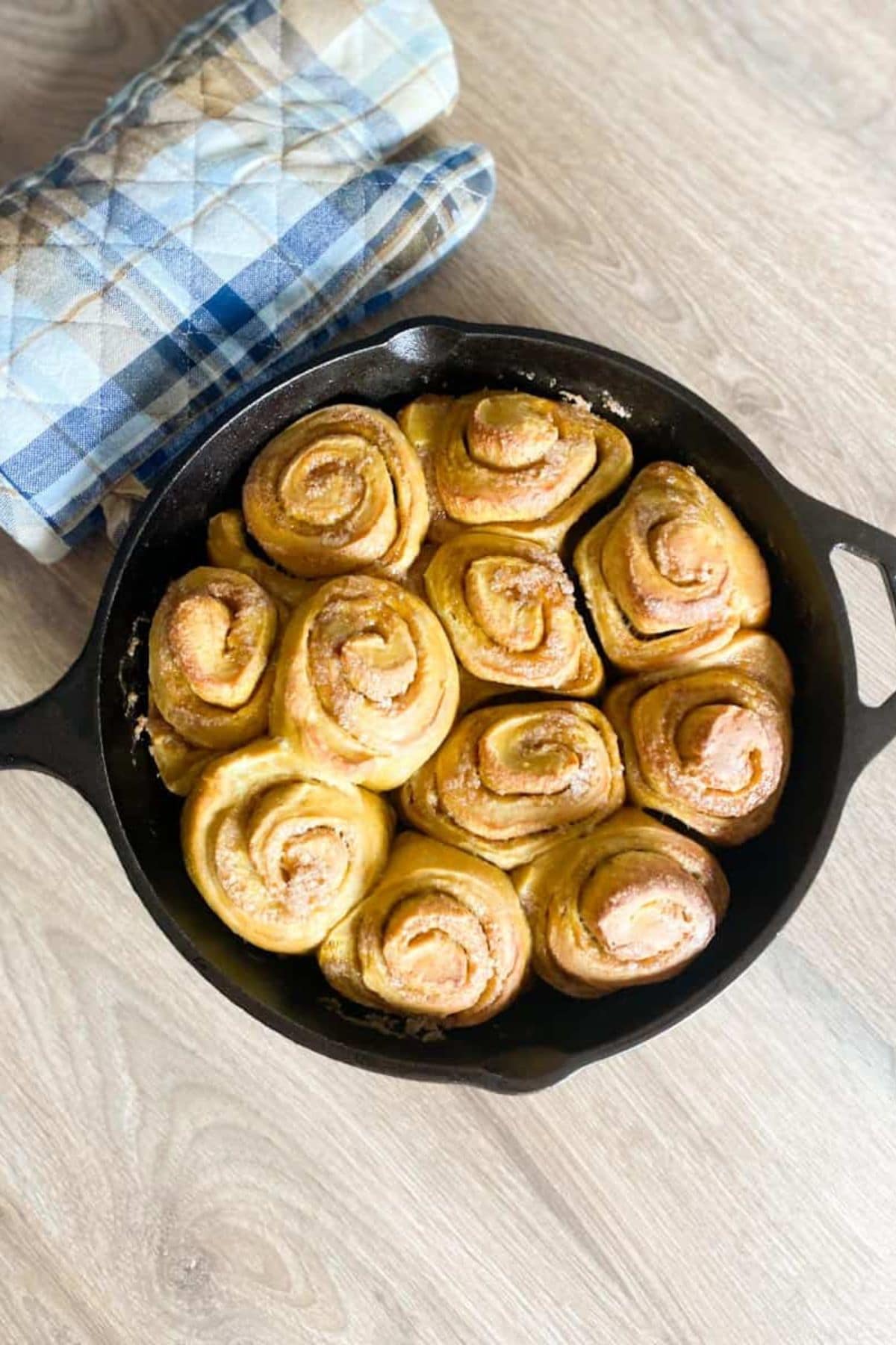Skillet filled with soft sourdough cinnamon rolls, swirled with pumpkin and dusted with warm spices.
