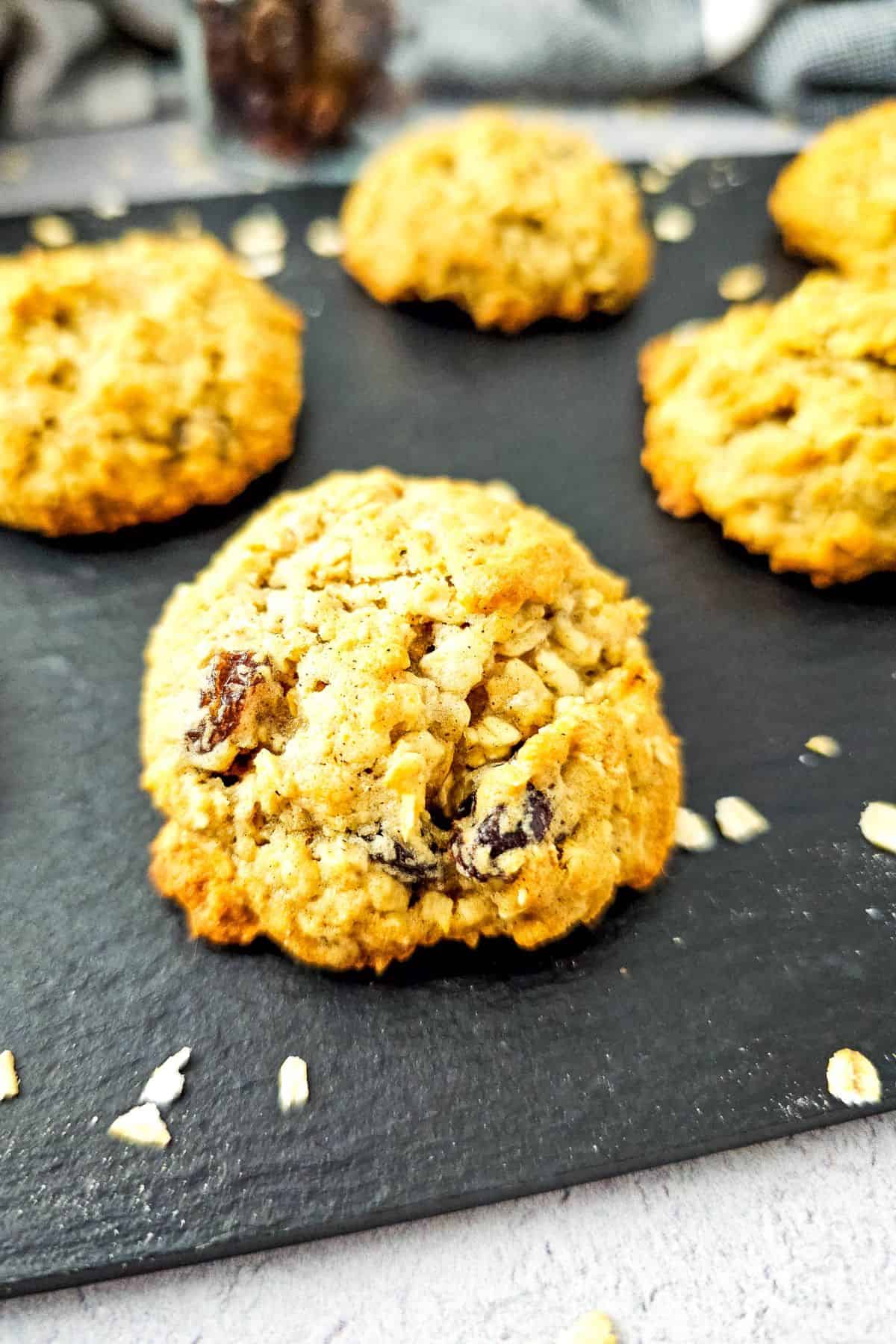 Soft and chewy cookies made with oats, raisins, and applesauce, arranged neatly on a wooden board.