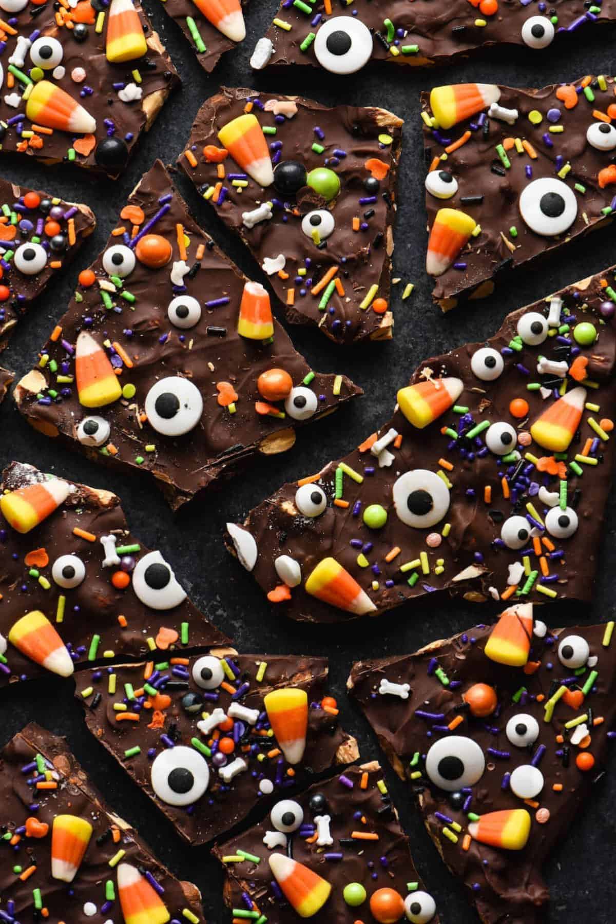 Cracked pieces of Halloween bark with colorful candy swirls spread out on a flat surface.