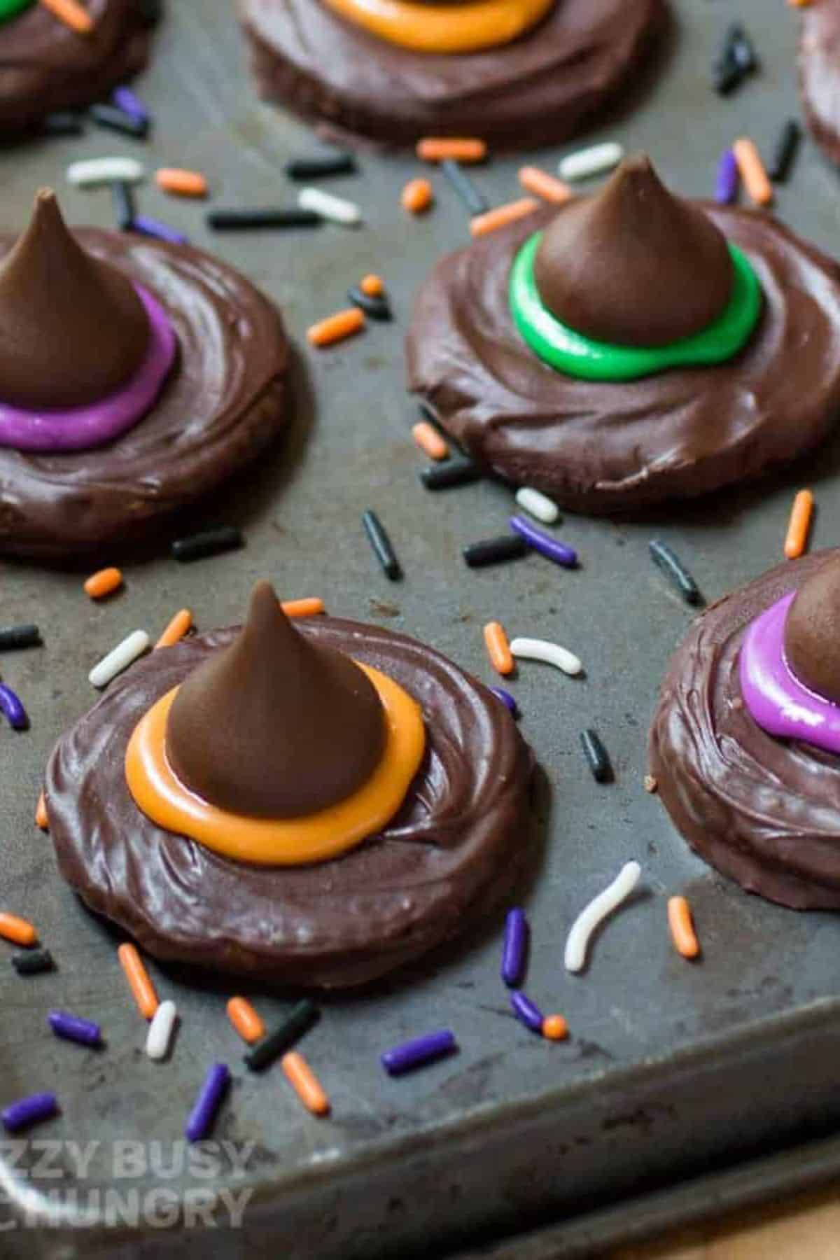 Close-up of Witch Hat Cookies on a flat surface, surrounded by festive sprinkles scattered around the cookies.