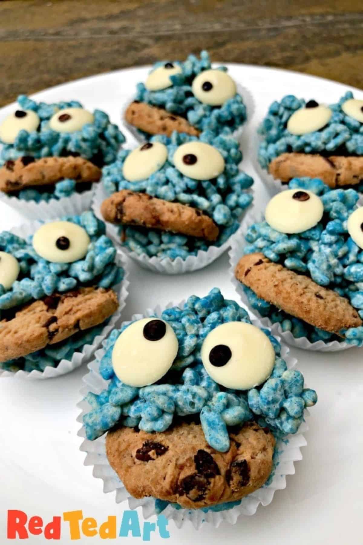 Blue rice crispy treats decorated with candy eyes and mini cookies, served on a plate and styled to look like playful cookie monsters.