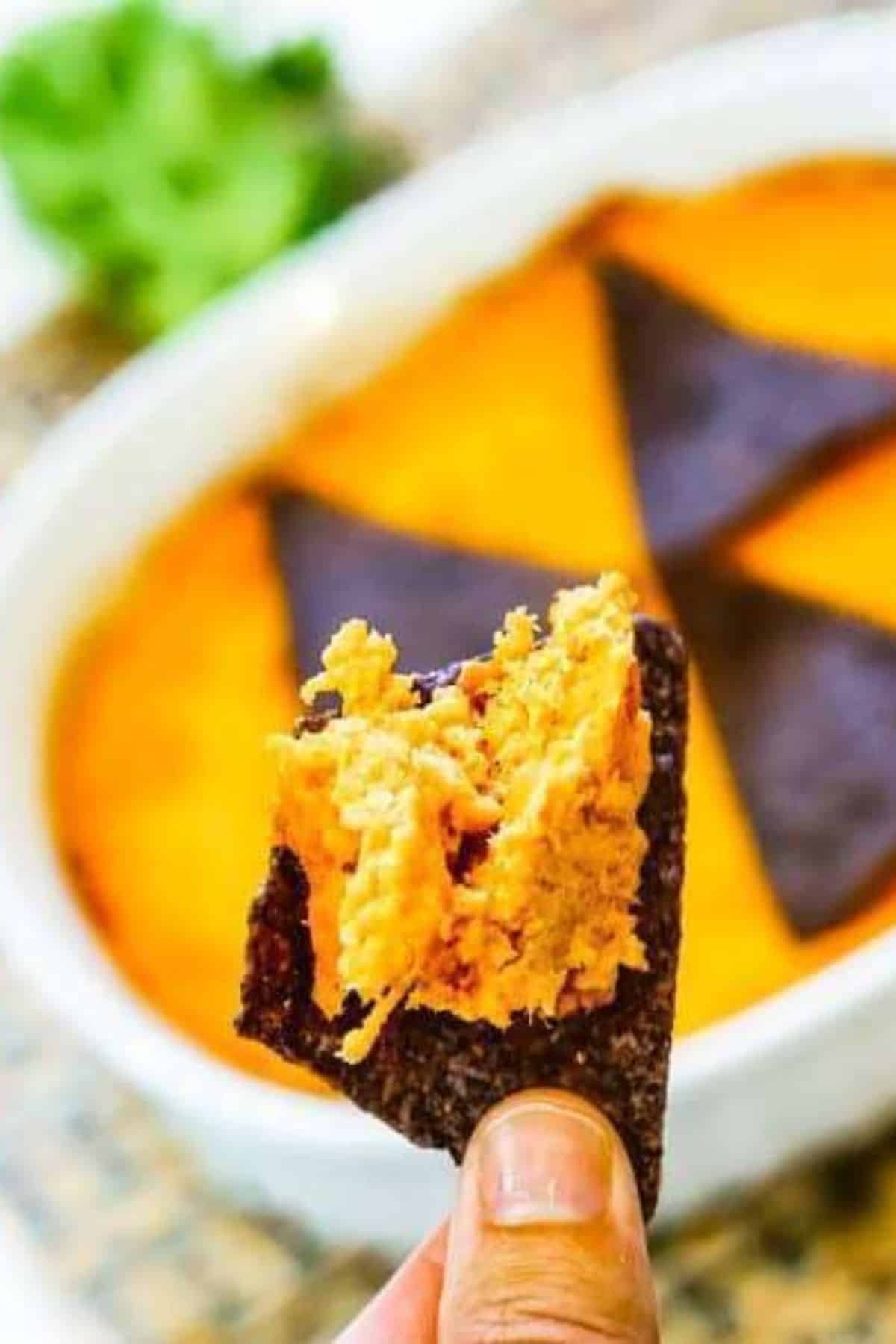 A hand holding a chip dipped into creamy Buffalo Chicken Dip.