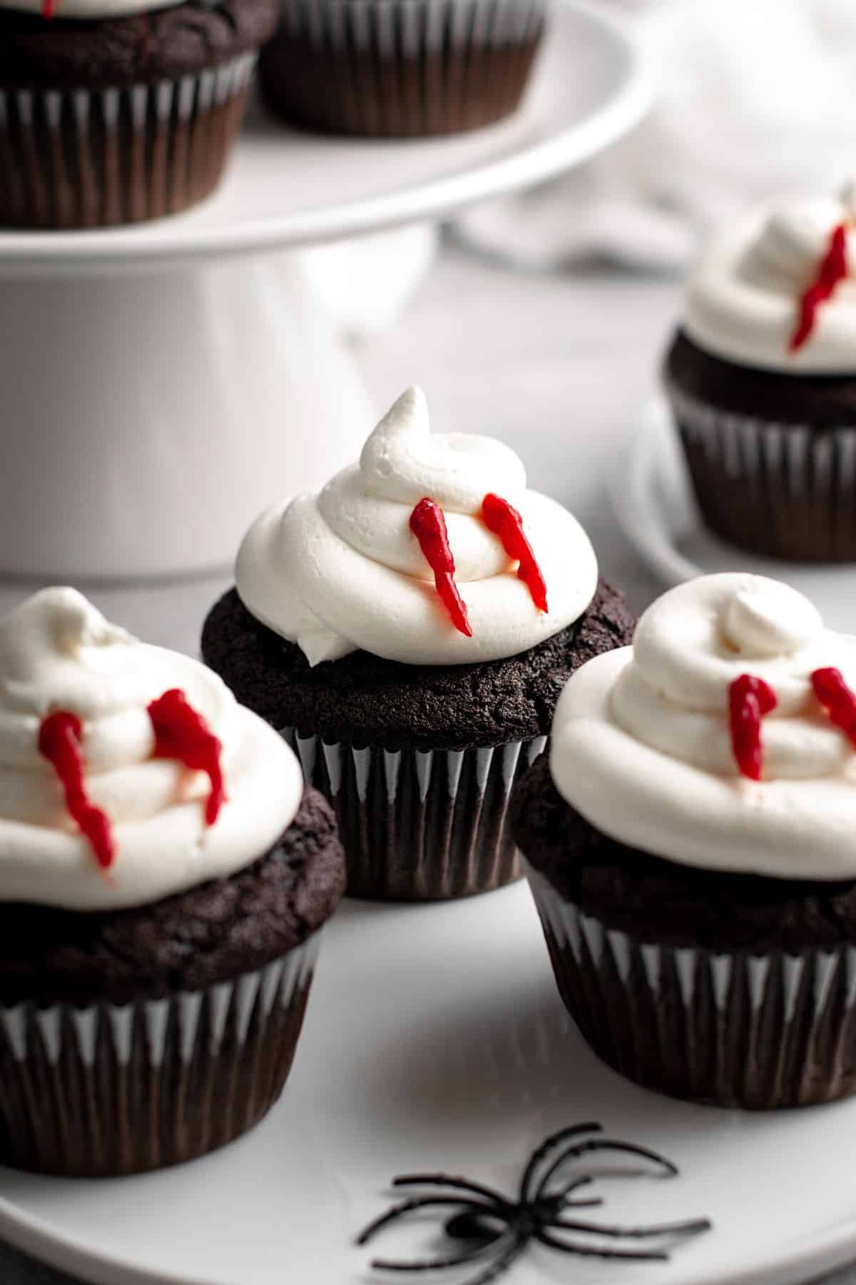 Chocolate cupcakes topped with vanilla frosting decorated to look like vampire bites.