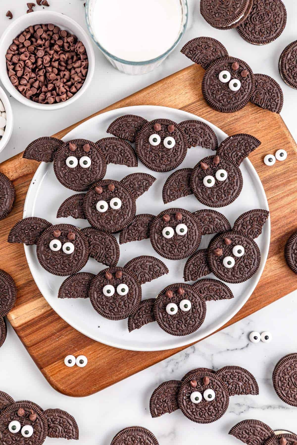 Bat-shaped Oreo cookies decorated with chocolate and candy eyes, arranged on a plate.