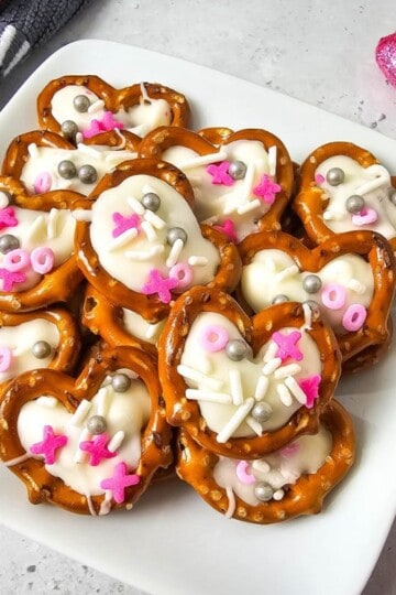 White chocolate pretzel hearts stacked on a plate, ready to serve.