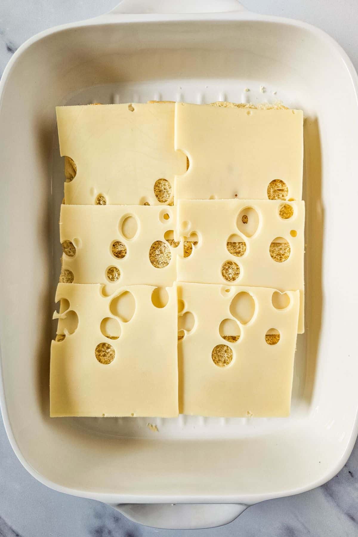 Cheese being placed on a slider half bun.