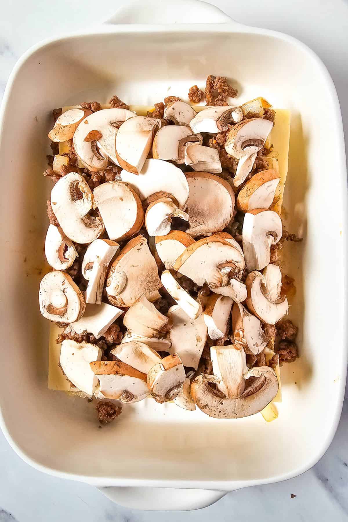 Cheese and ground beef topped with mushrooms on a slider half bun.