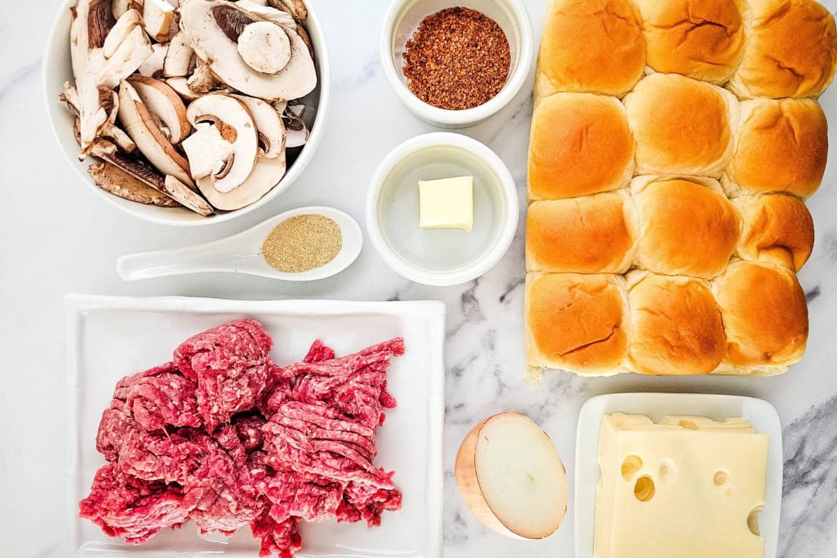 Ingredients of mushroom swiss sliders arranged in a surface.