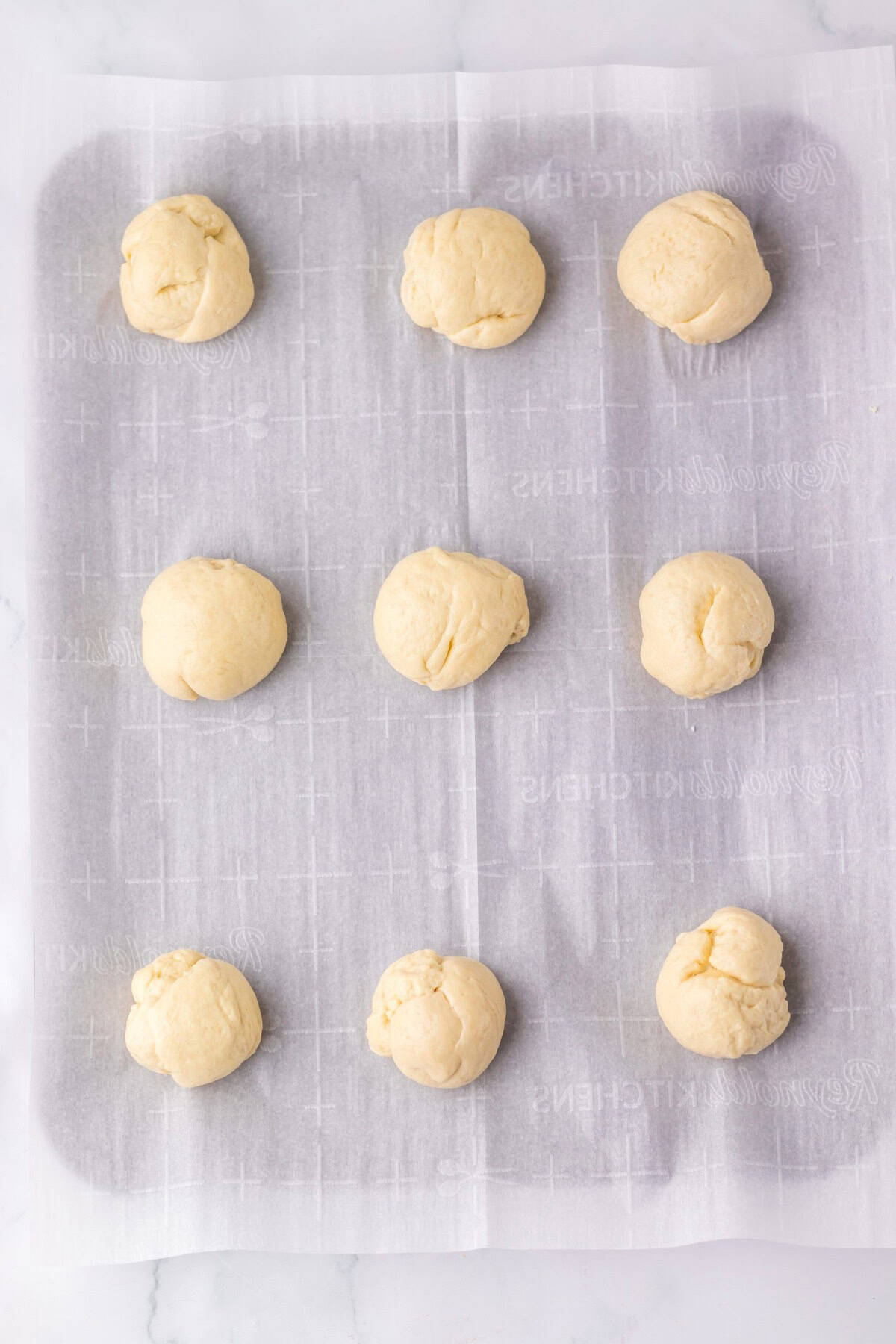 Dough balls in a baking pan resting on a cloth.