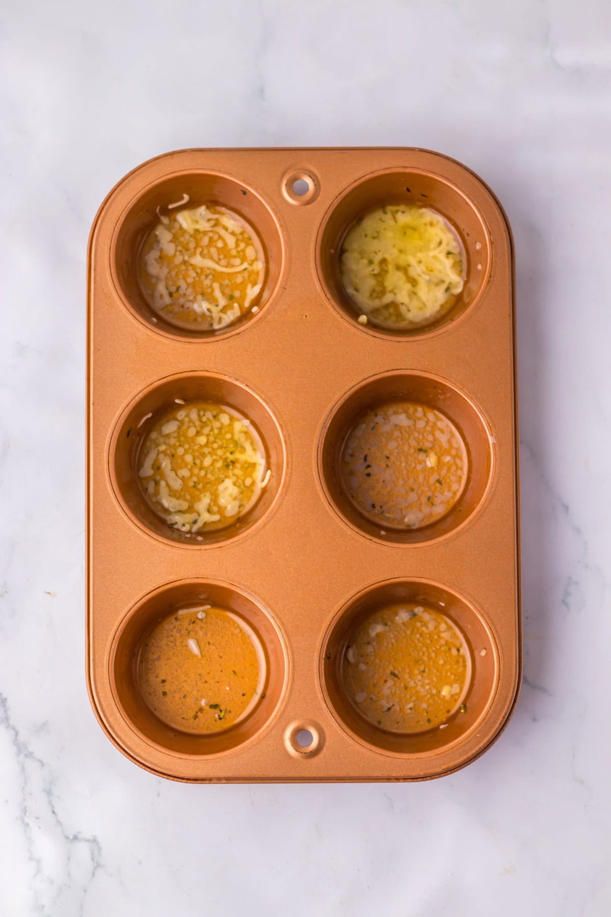 Garlic butter mixture being added to a muffin tin/