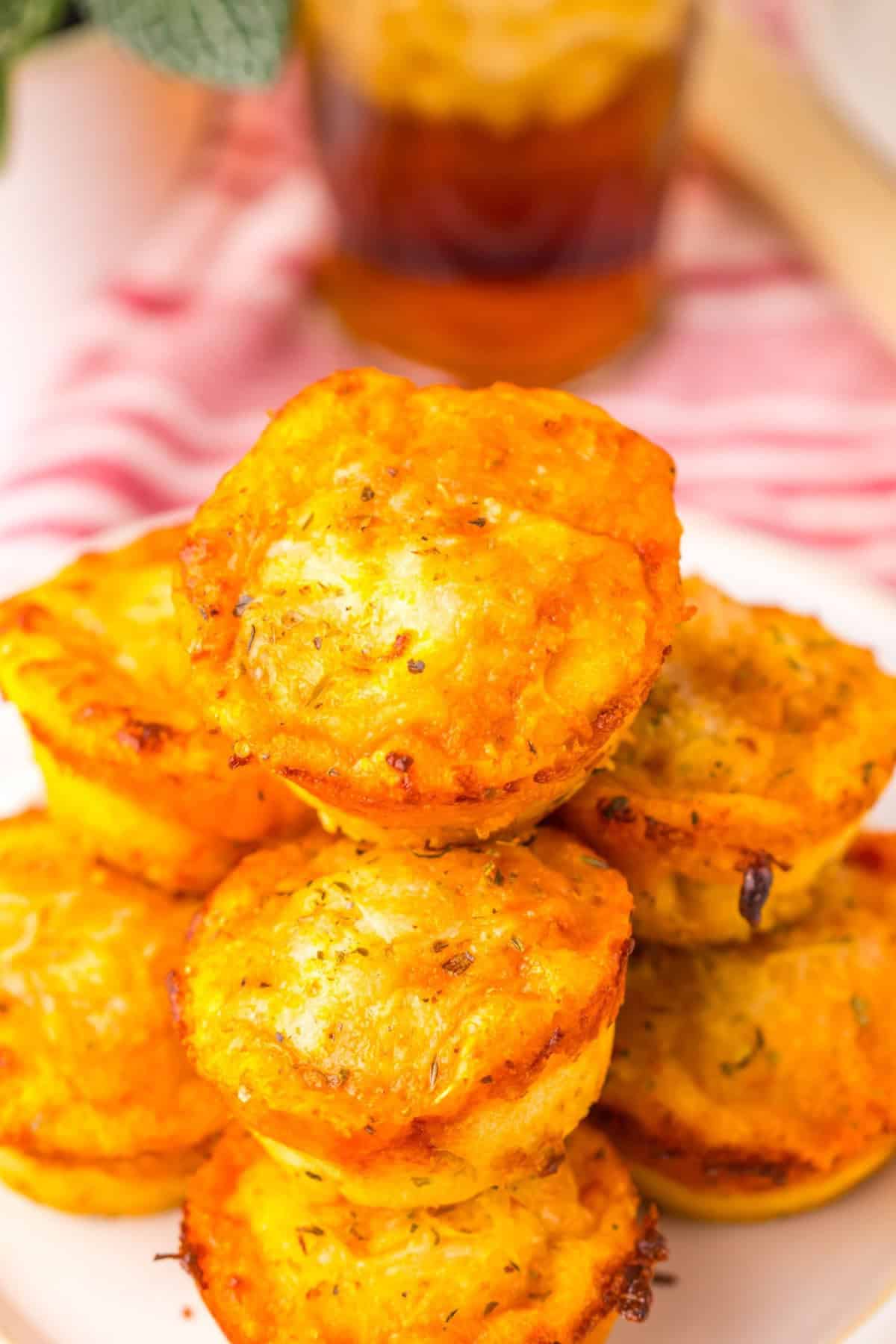 Stack of cheesy muffin tin pizza puffs served on a white plate.