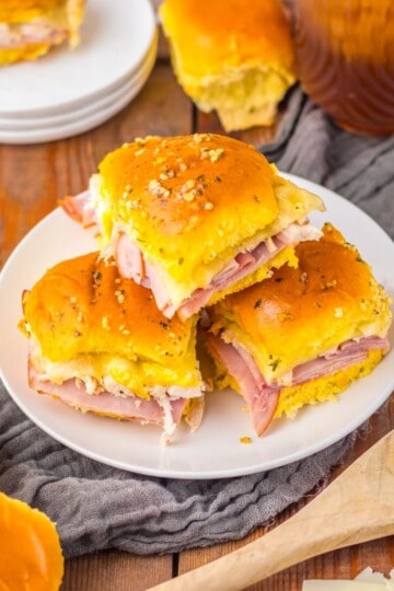 Chicken cordon bleu sliders served on a plate with a cloth underneath with spatula nearby.
