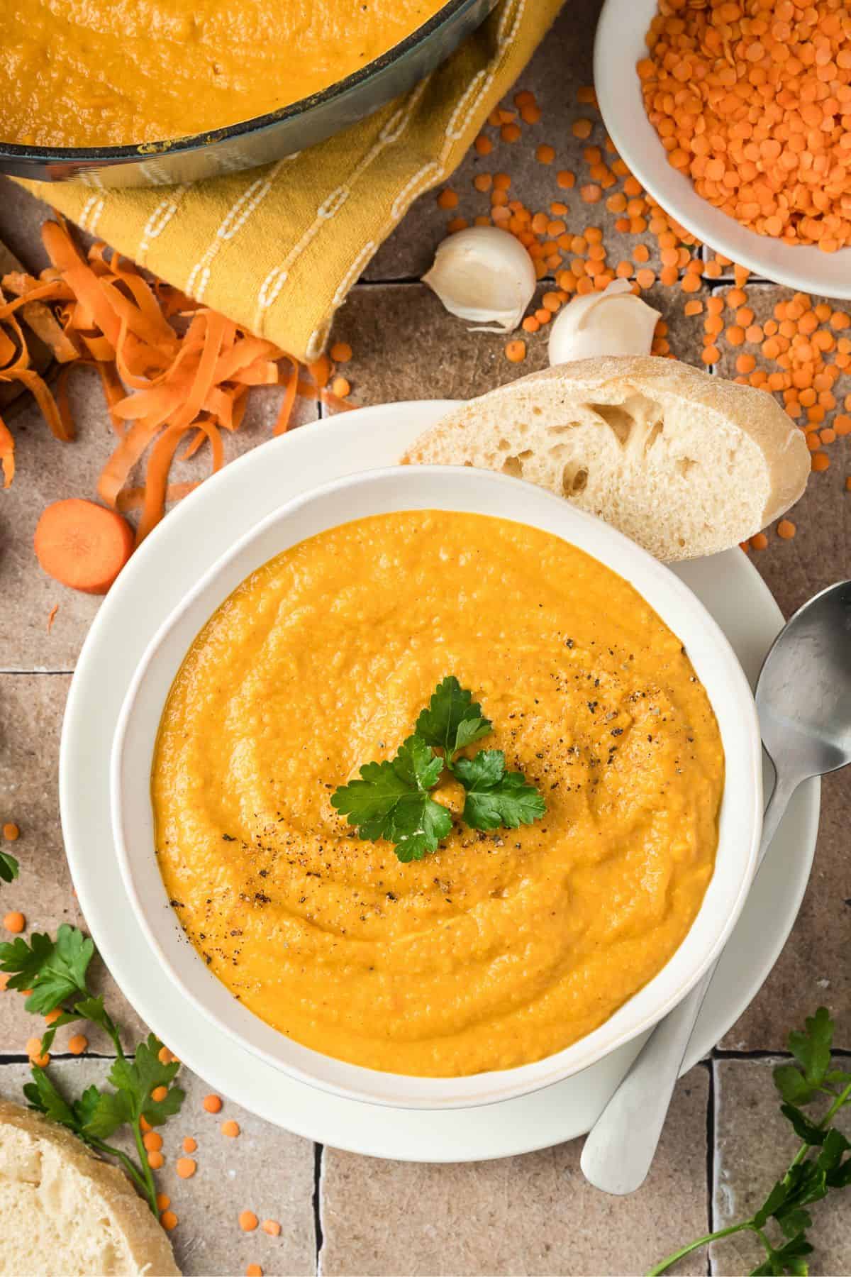 A bowl of creamy soup with garlic bread resting on it.