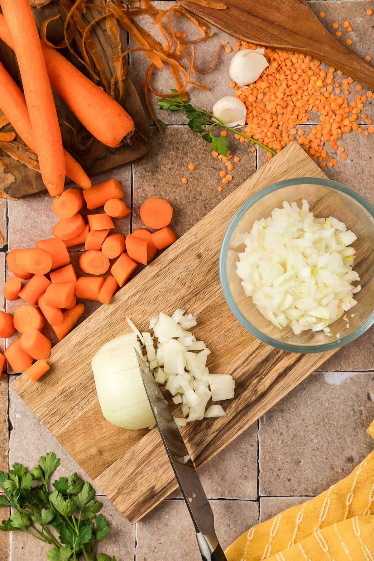 Sliced onions on a cutting board with a bowl of sliced onions beside them.