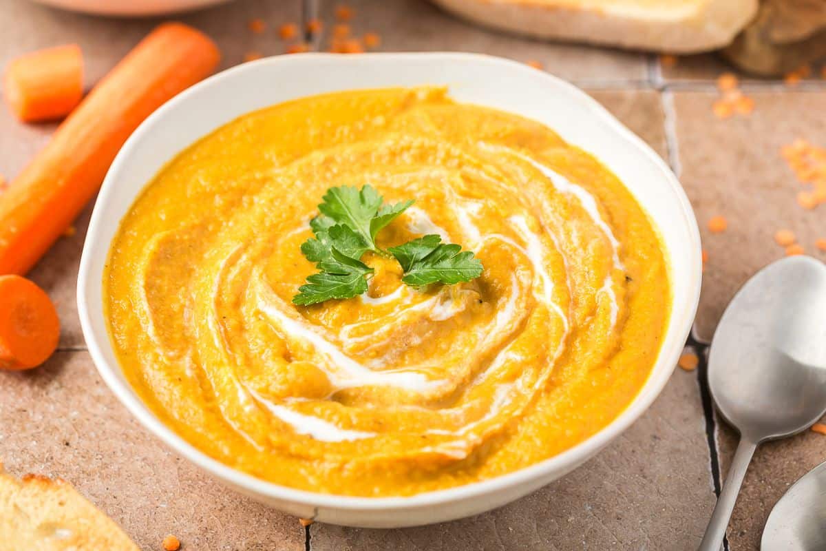 A bowl of creamy soup with garlic bread resting on it.