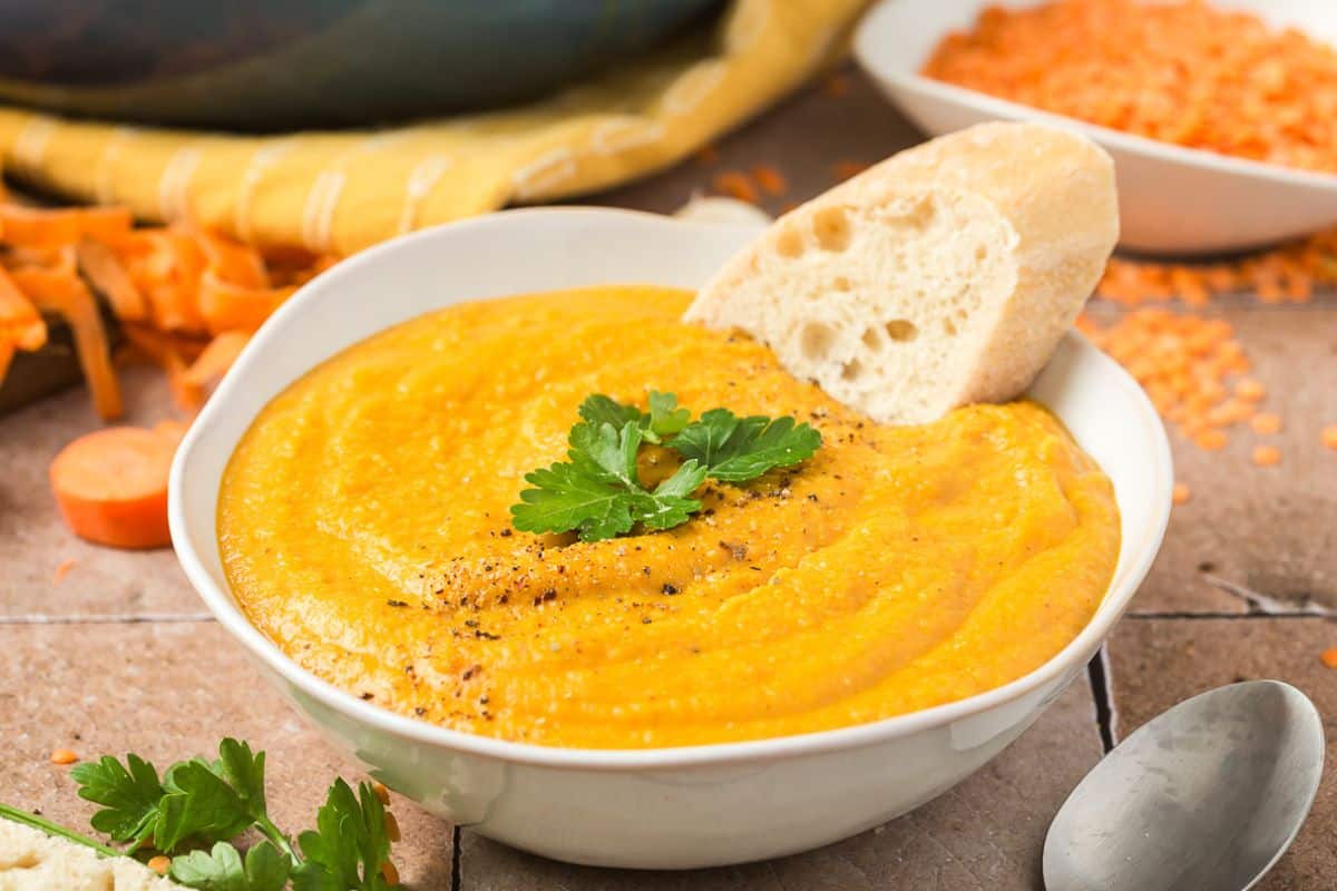 A bowl of creamy soup with garlic bread resting on it.
