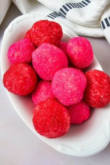A plate of cake mix cream cheese truffles coated in pink and red sanding sugar, ready to serve.