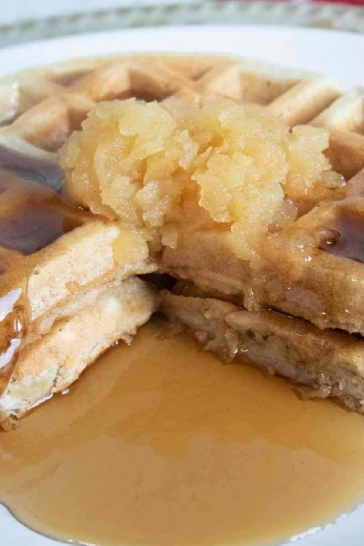 Applesauce waffles with cinnamon, sliced and served on a plate with maple syrup drizzled.