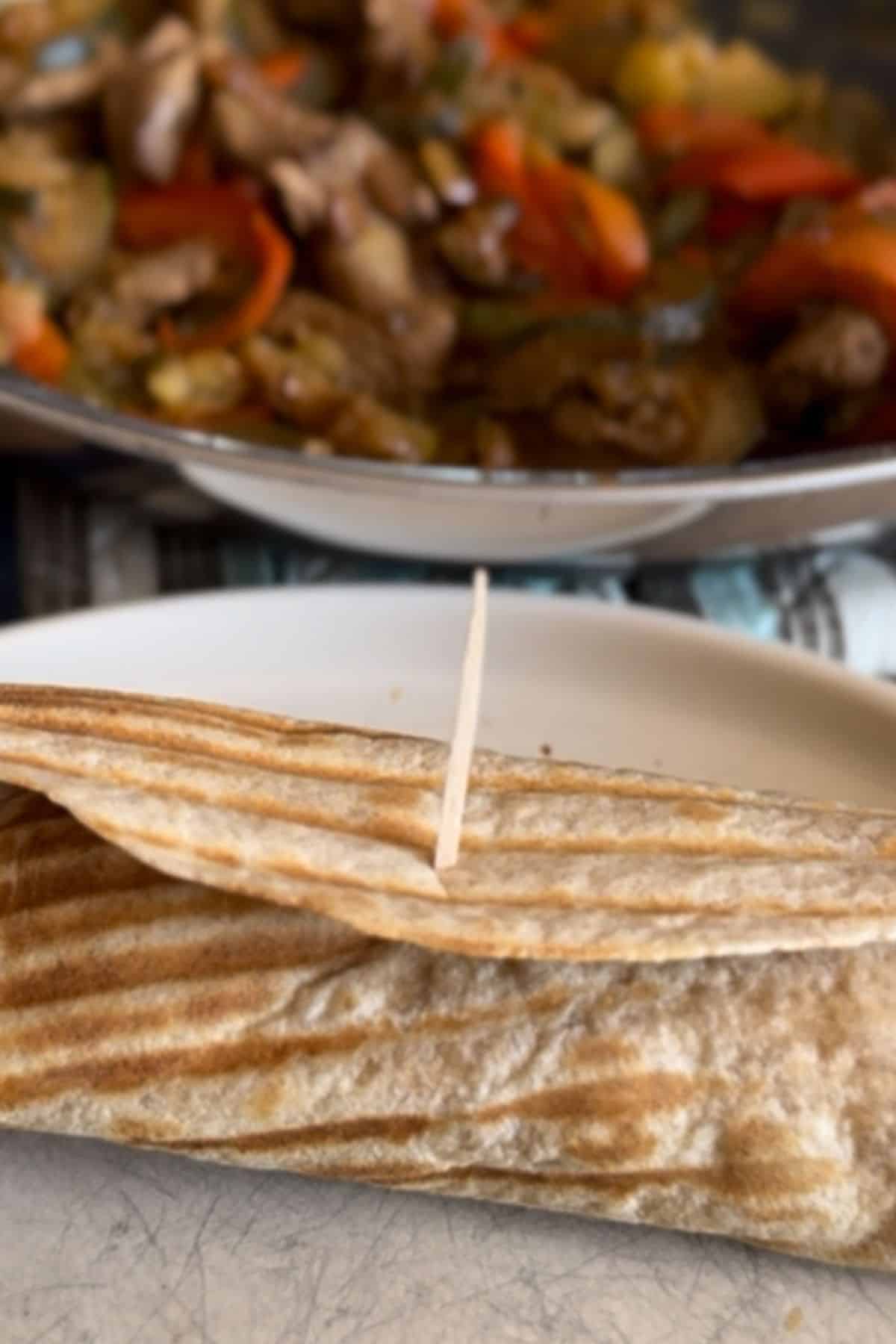 Served beef strip fajita wrap with toothpick resting on it.