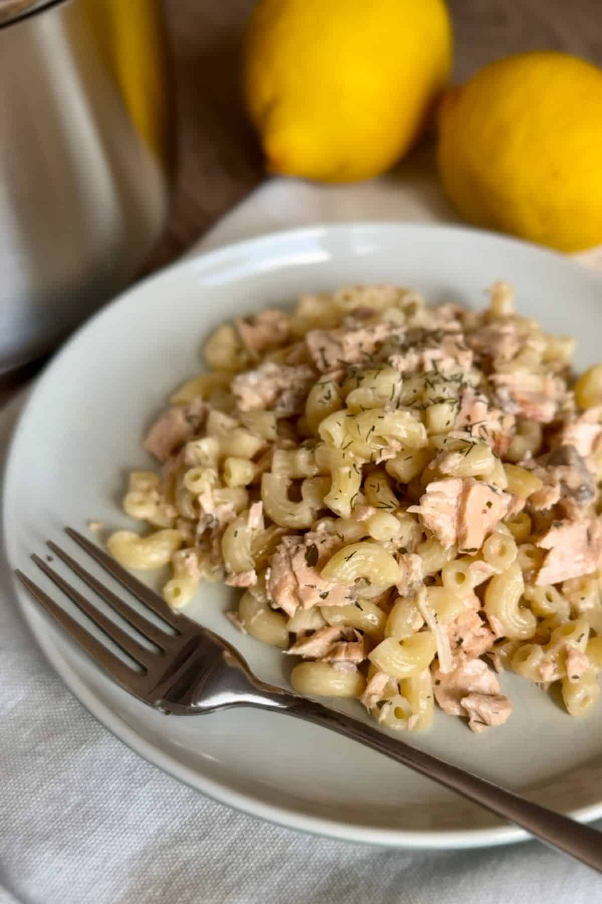 A plate with creamy dill salmon pasta with fork beside it.