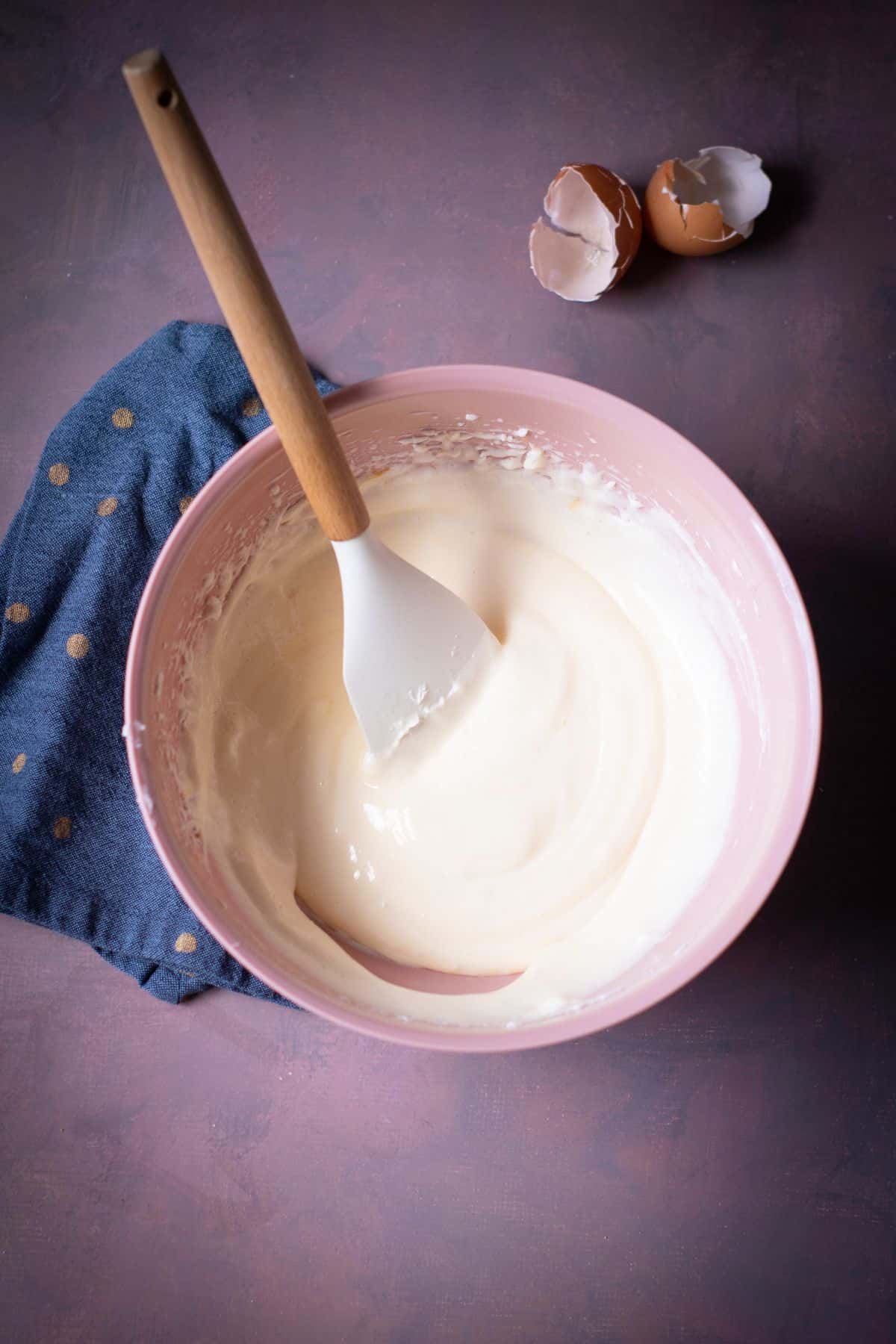 A bowl with ingredients being mixed and a spatula resting on it.
