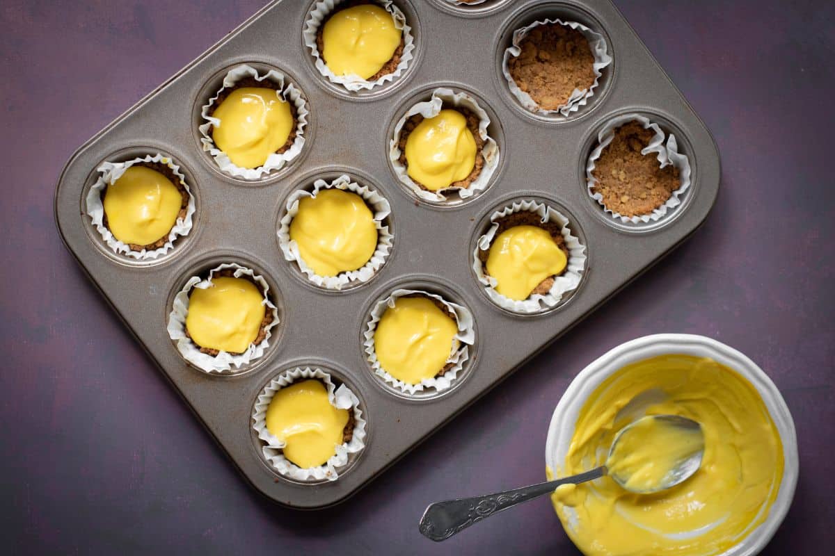 A tin can being filled with yellow cheesecake batter.