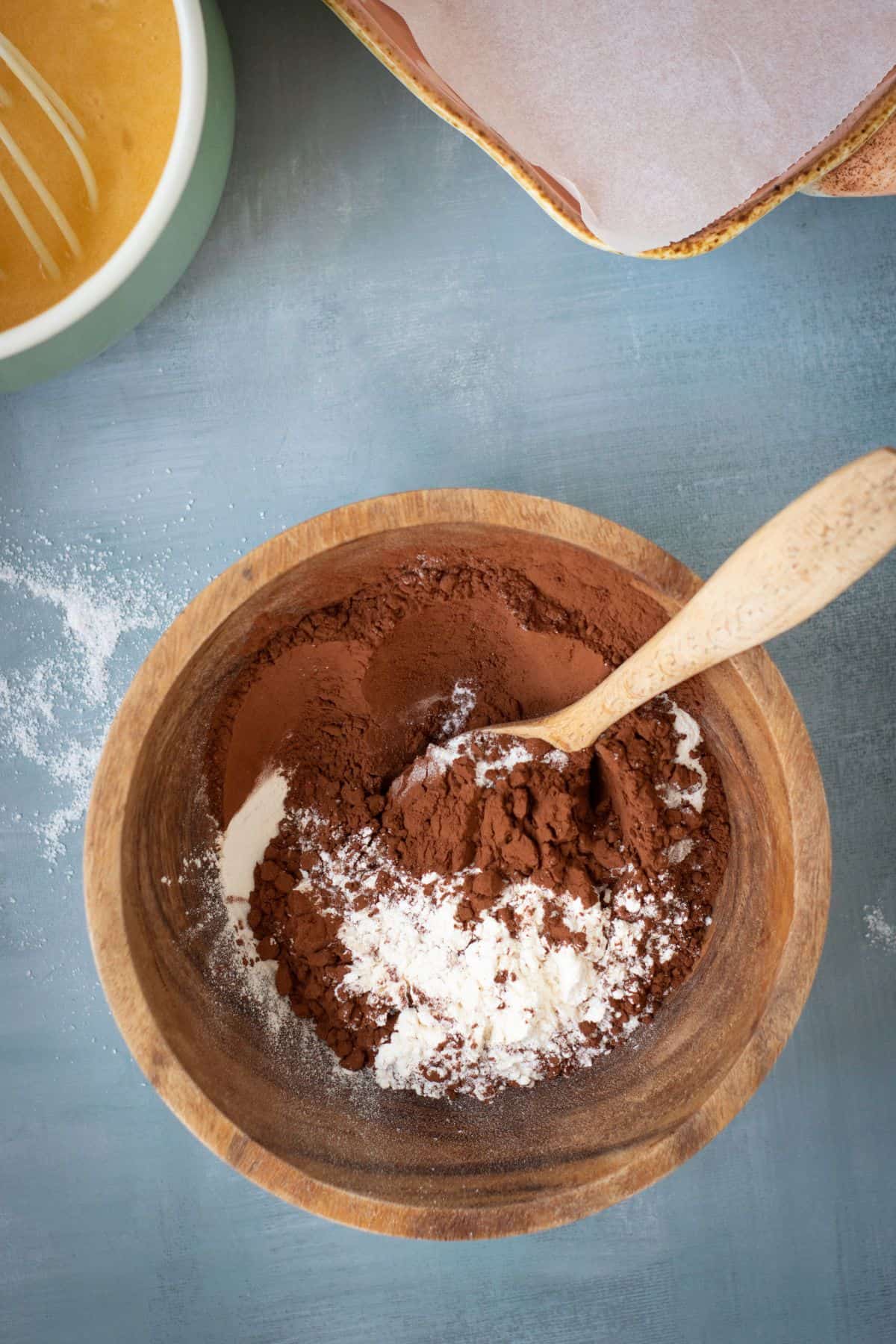 A chocolate brownie batter being mixed in a rustic large mixing bowl with a spatula.