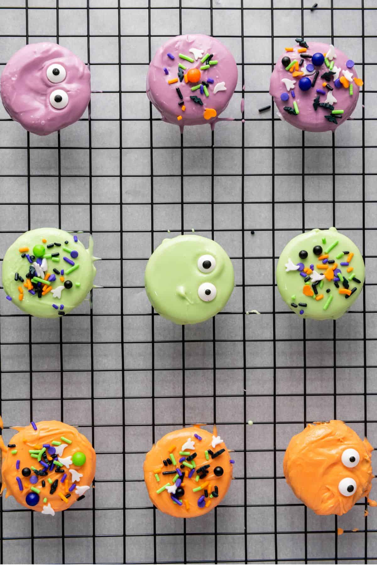 Halloween cookies on a cooling rack, each topped with colorful sprinkles.