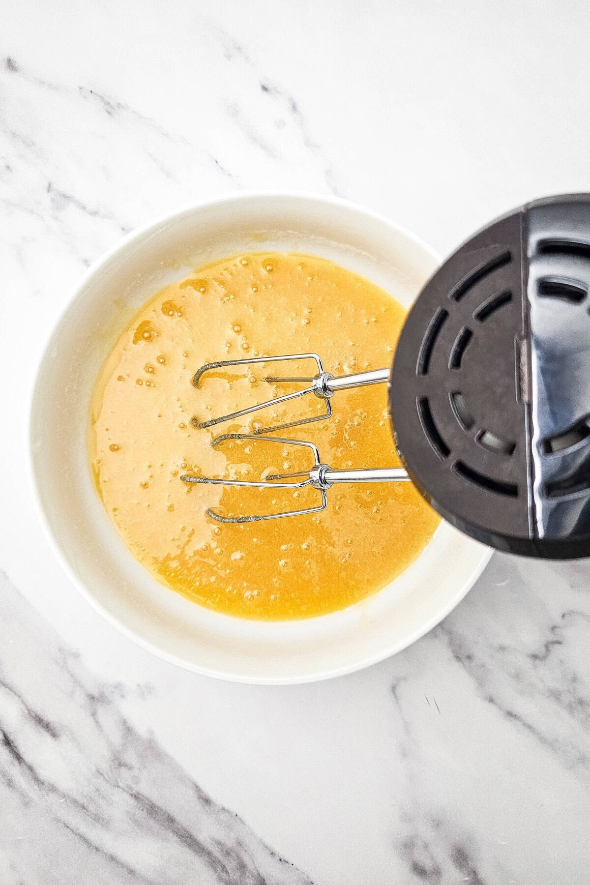 An egg being mixed in a bowl with an electric mixer.