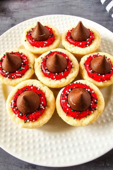 Christmas Kiss Cookies arranged on a plate, topped with Hershey’s Kisses and festive red, green, and white sprinkles.