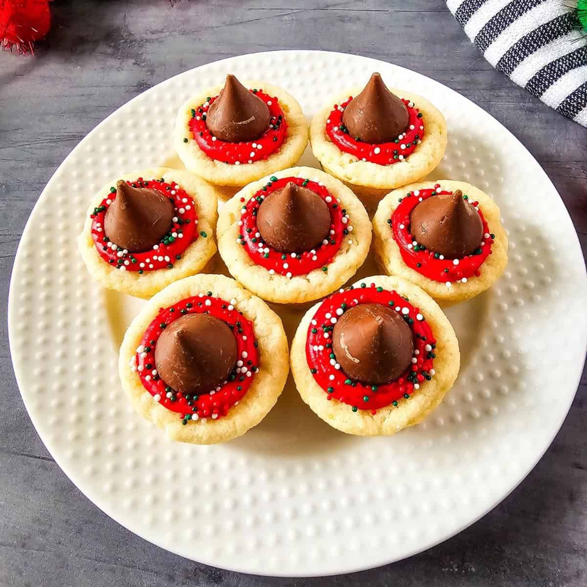 Christmas Kiss Cookies arranged on a plate, topped with Hershey’s Kisses and festive red, green, and white sprinkles.