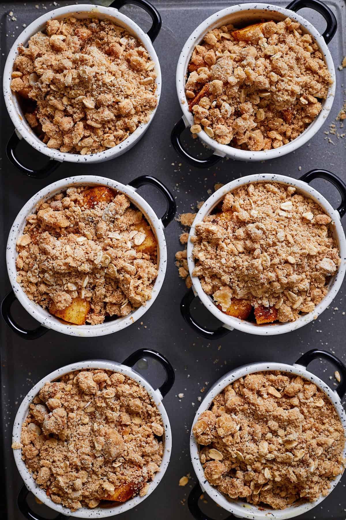 A rameskins with apple crumble topped with a golden, crunchy oat topping.