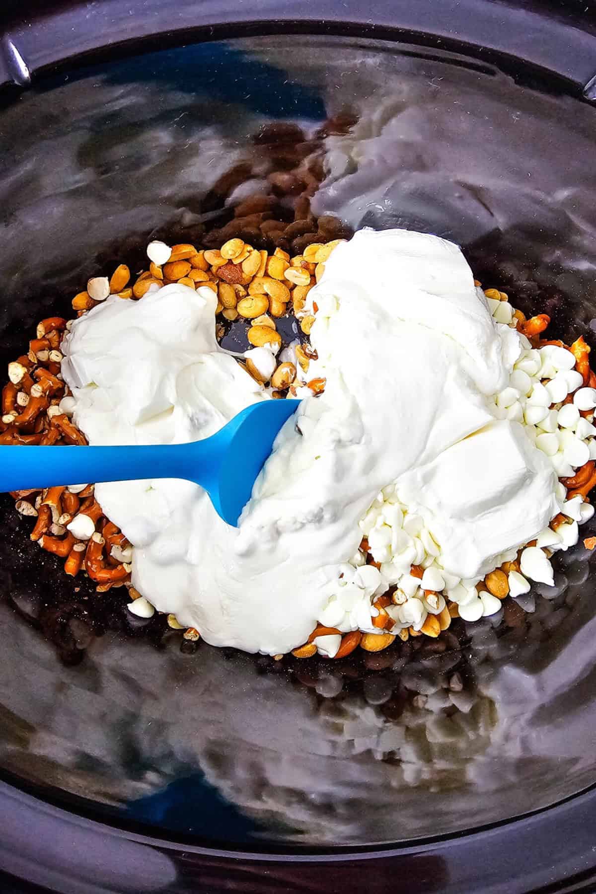 Ingredients being mixed in a crockpot with a spatula.