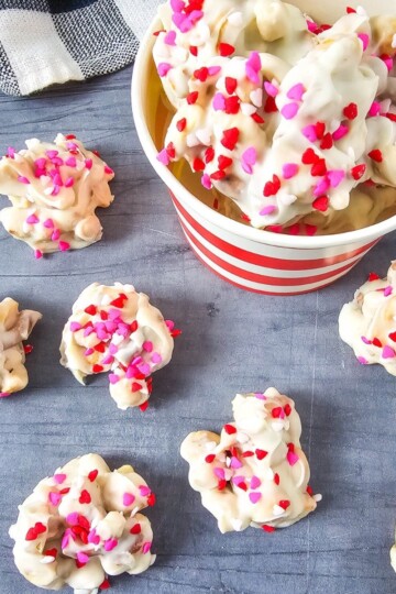 White chocolate candies on a surface next to a bucket of more candies.