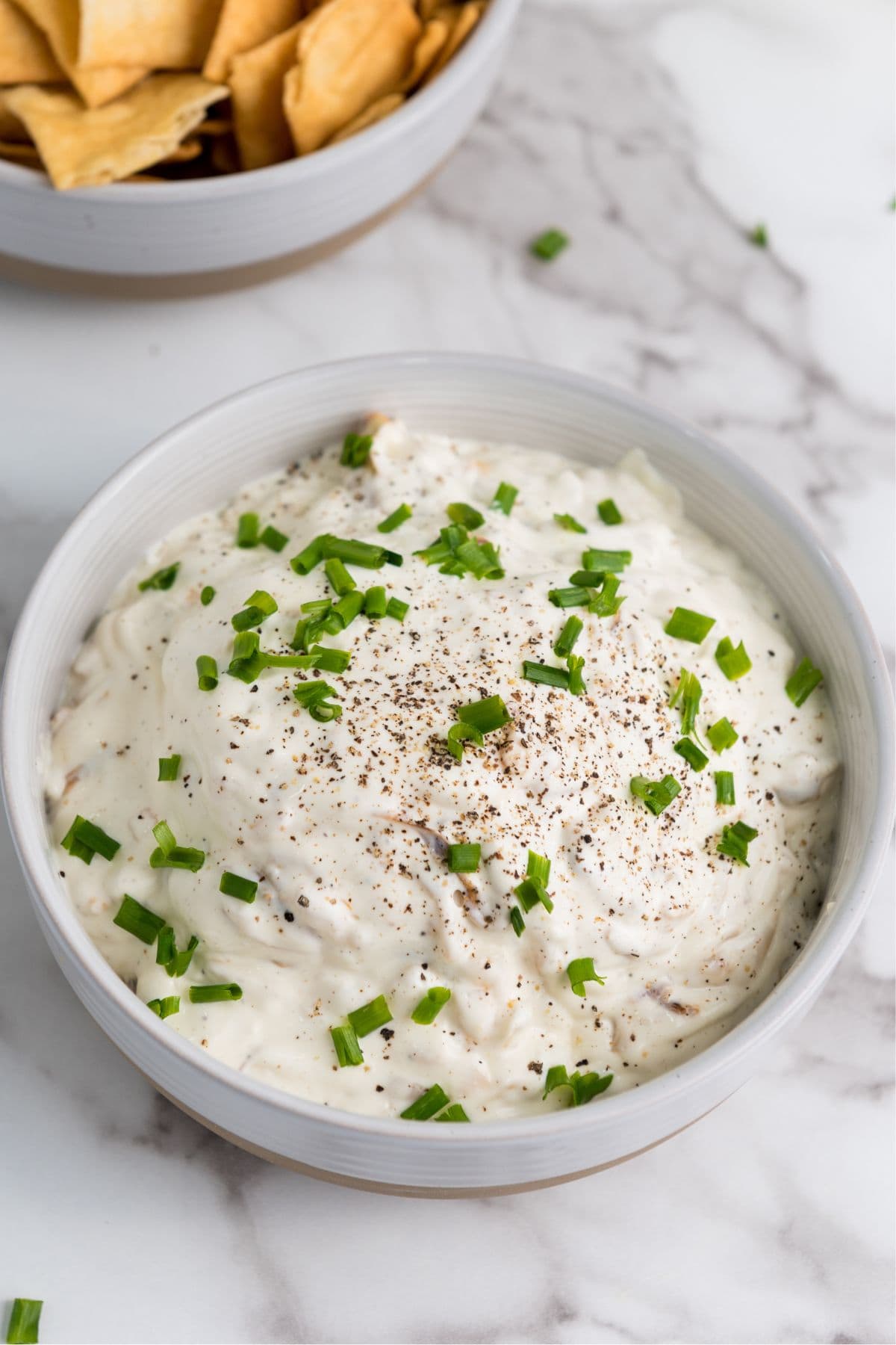 Caramelized onion dip served in a bowl with crackers on the background. 