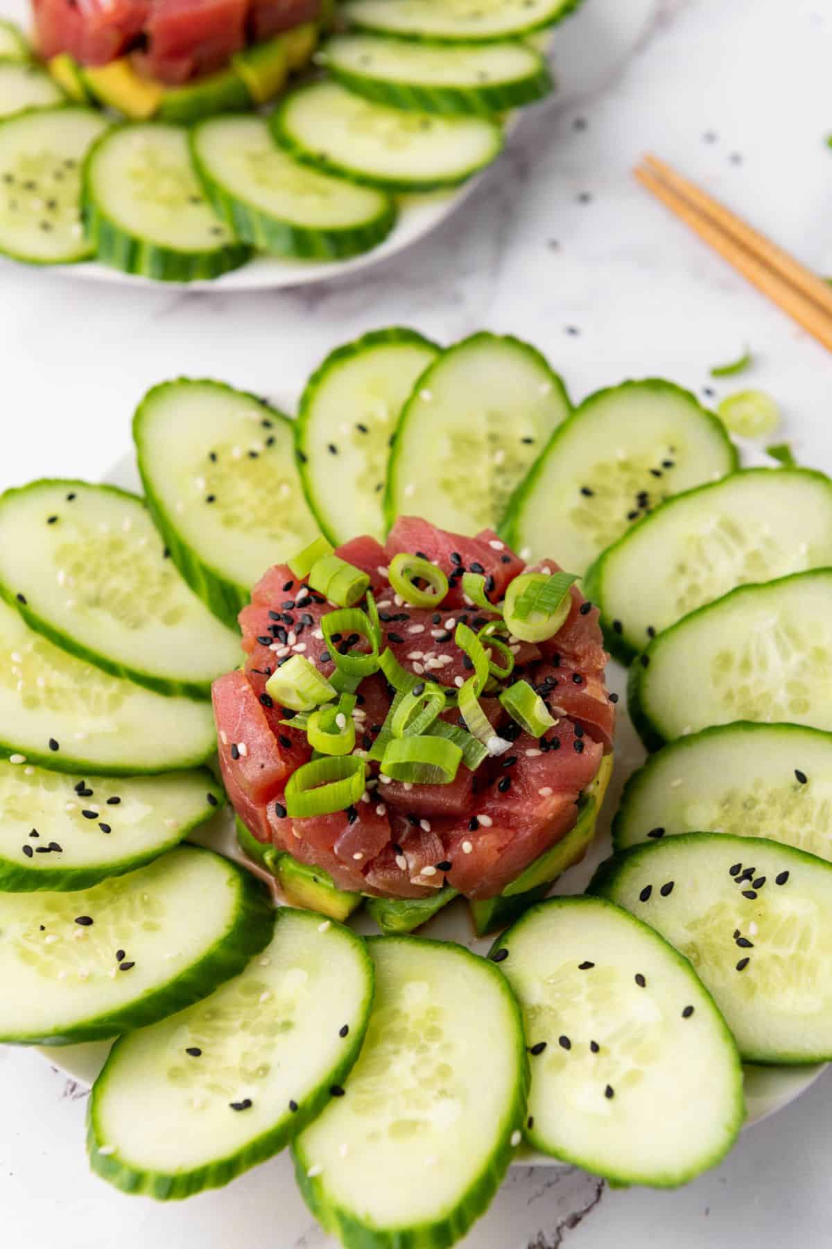 Tuna placed in the center of a plate, surrounded by slices of cucumber.