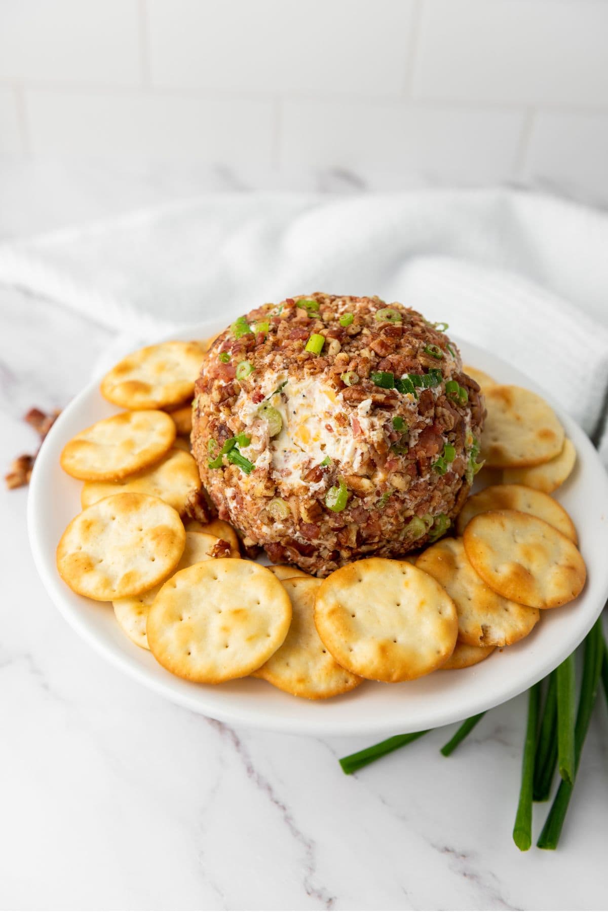 Pecan bacon cheeseball placed in the center, surrounded by crackers.