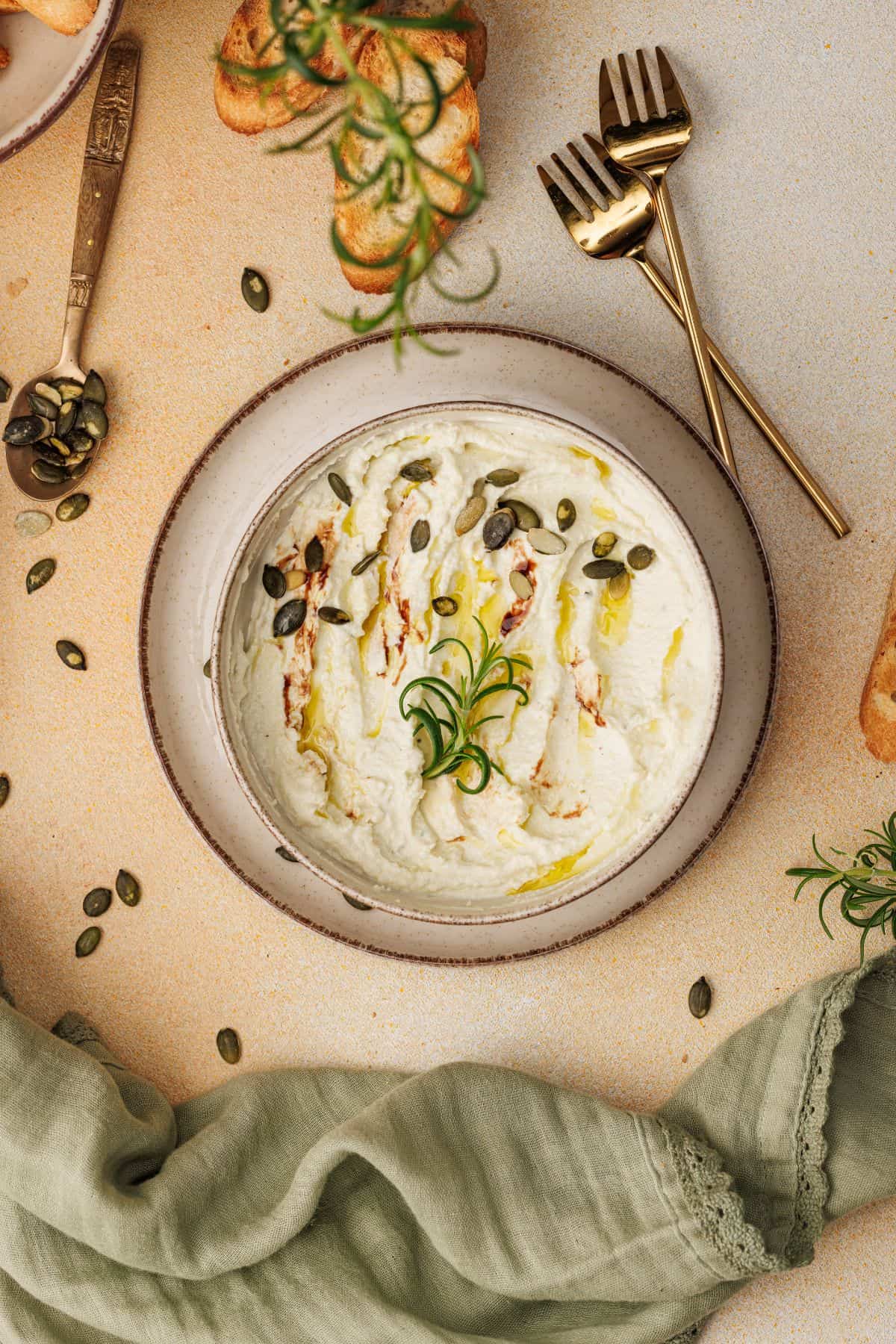 Creamy baked goat cheese dip served in a bowl, topped with a sprinkle of garnish.