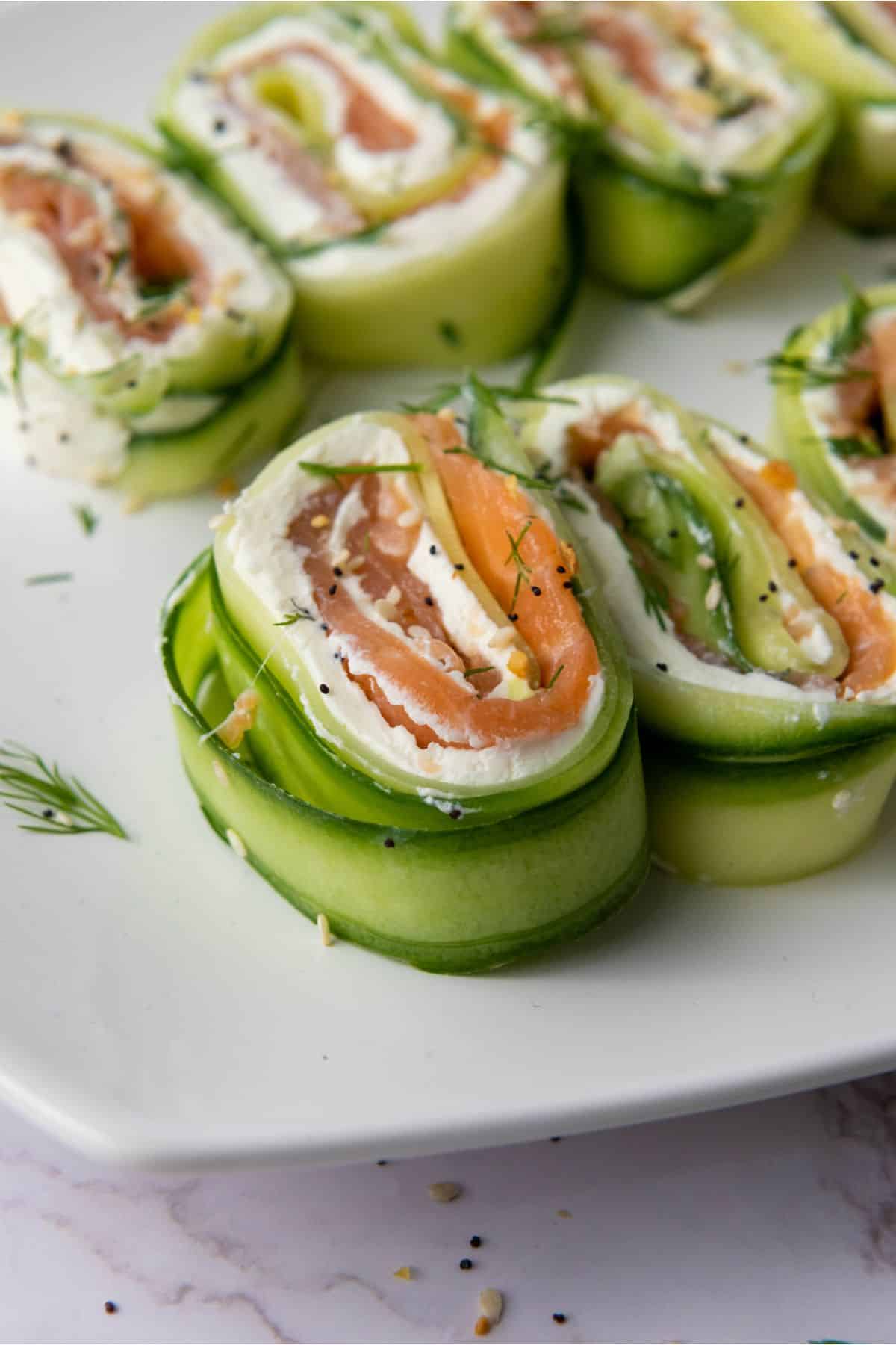 Close-up photo of salmon cucumber rolls arranged on a plate.