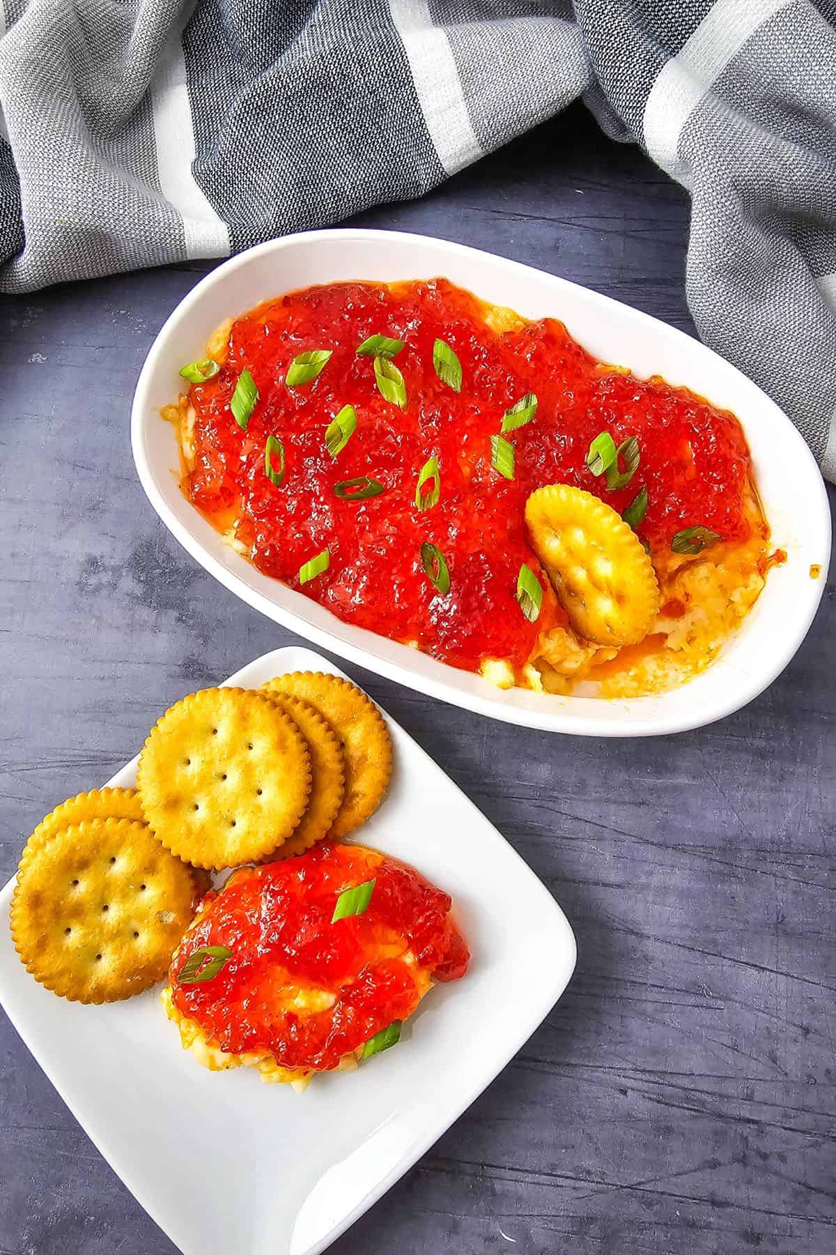 Plate with a bowl of jelly pepper dip and biscuits, with some biscuits resting on the edge of the bowl.