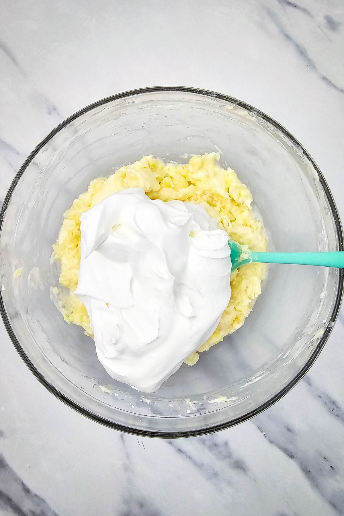 Cream cheese mixture in a bowl being combined with whipped topping using a hand mixer.