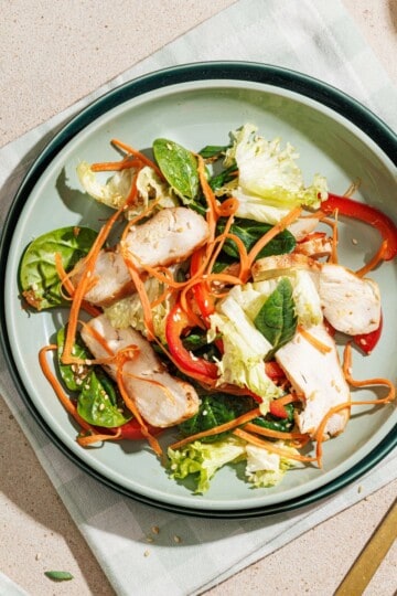 Asian salad served on a white plate, resting on a cloth napkin.
