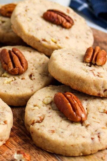 Stack of buttery pecan cookies on a wooden board.