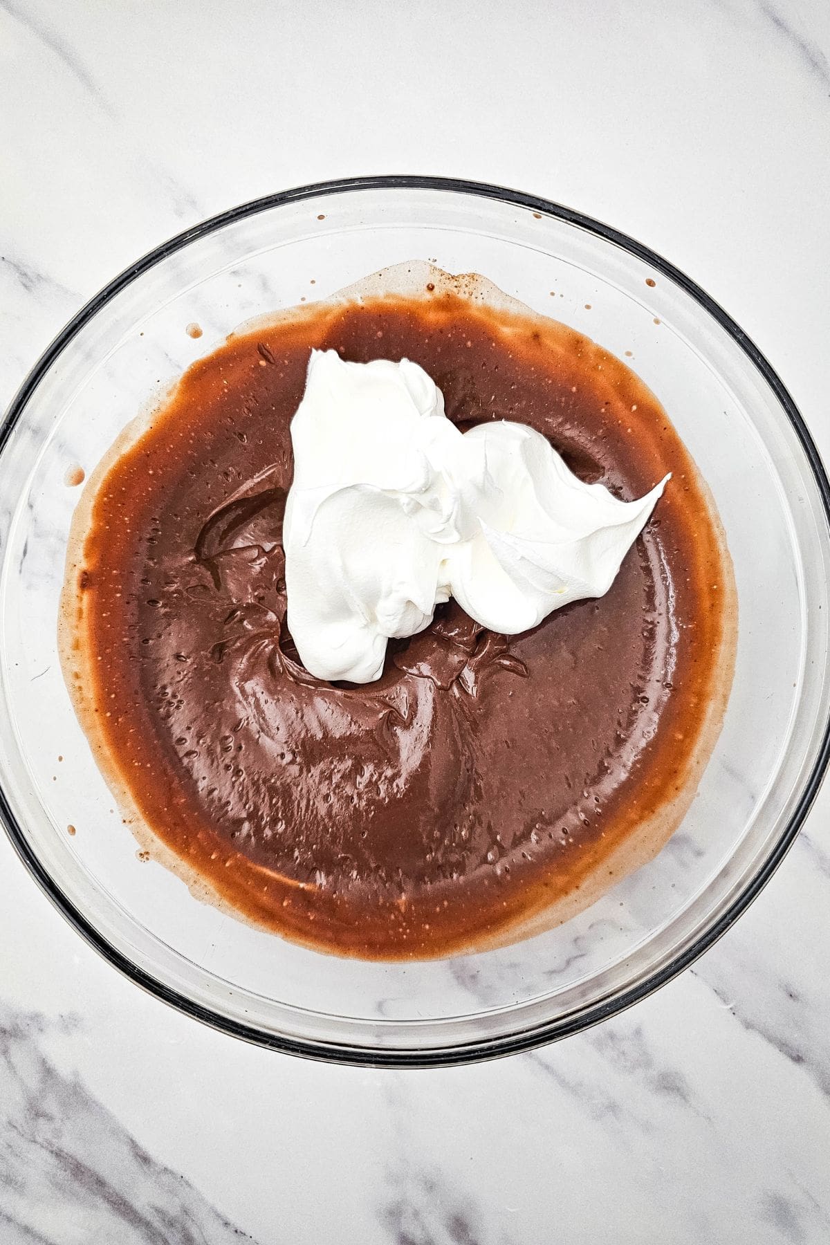 Chocolate pie with a chocolate crust filled with a silky chocolate mixture and topped with a dollop of whipped cream in a bowl.