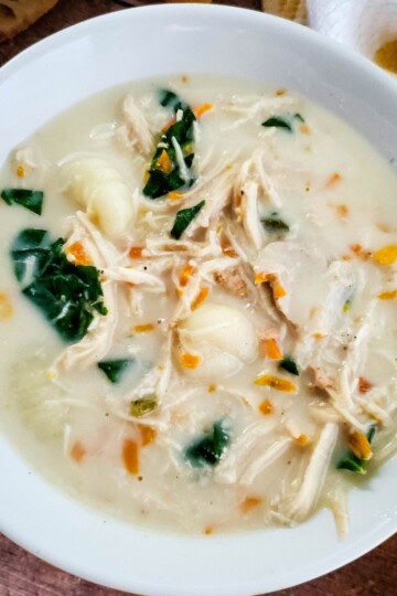 Creamy crockpot chicken gnocchi soup served in a bowl with visible spinach and chicken pieces.