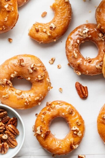Donuts placed on a surface, surrounded by colorful sprinkles and sliced almonds.