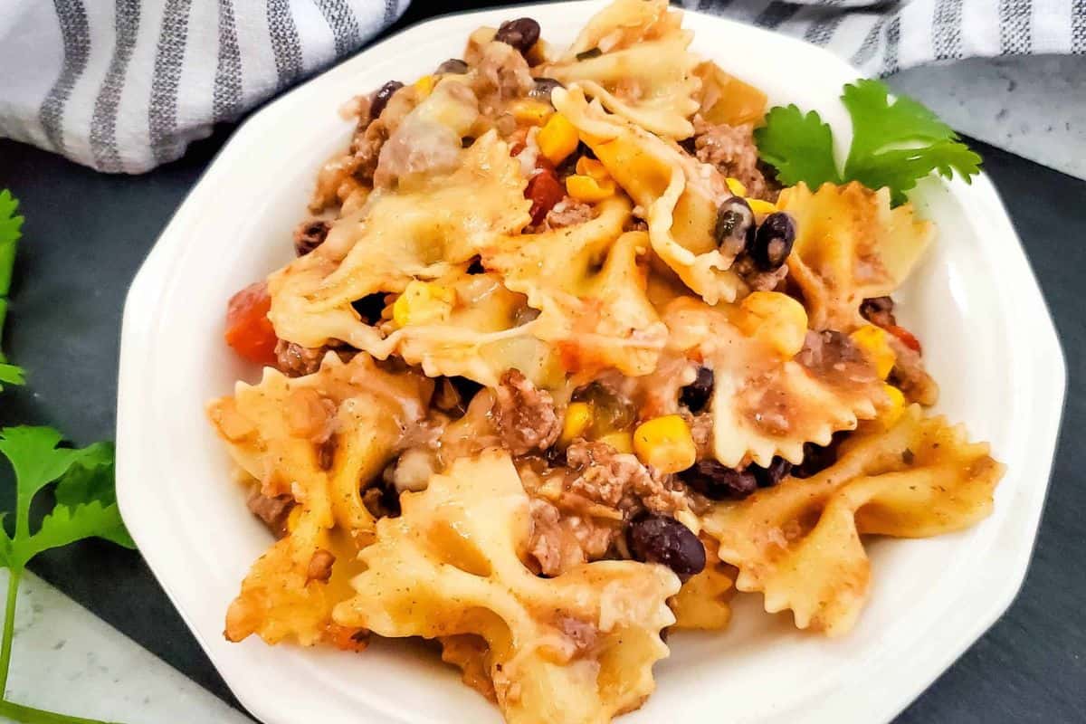 Close-up photo of tex-Mex pasta served on a plate with a cozy cloth background.